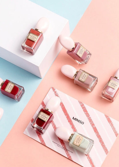 seven nail polish bottles: three dusty pink, two dark red, one dark orange, and one off white