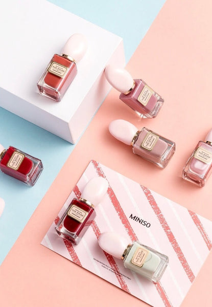 seven nail polish bottles: three dusty pink, two dark red, one dark orange, and one off white