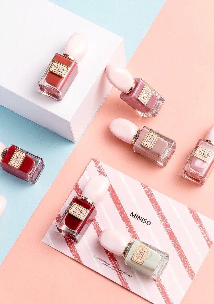 seven nail polish bottles: three dusty pink, two dark red, one dark orange, and one off white